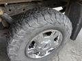 A close-up of a rugged tire on a chrome wheel from a 2014 Ford F-150 showcasing deep treads designed for off-road performance