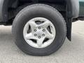 A close-up view of a silver alloy wheel on a 2004 Toyota Tacoma featuring five spokes and a black tire with visible tread pattern