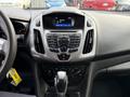 Interior view of a 2017 Ford Transit Connect showcasing the dashboard with audio controls and a display screen indicating the time and radio station. Gear shift is visible in the foreground