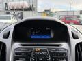 A dashboard of a 2017 Ford Transit Connect displaying the radio interface with the station name and time