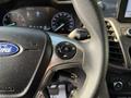 Close-up of the steering wheel of a 2019 Ford Transit Connect featuring the Ford logo and a control button for voice command or audio settings
