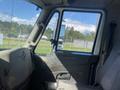 Interior view of a 2014 International 7400 truck showing the driver's seat and dashboard with controls and a large side window
