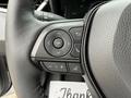 Close-up of a steering wheel control panel featuring buttons for navigation volume and phone functions in a 2025 Toyota Corolla