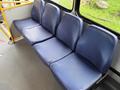 A row of blue bus seats with a textured surface arranged against a window