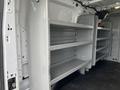 A 2017 Ford Transit van with metal shelving units installed inside the cargo area