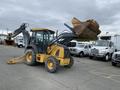A yellow and black 2012 John Deere 310SJ backhoe loader with a raised front bucket and an articulated arm ready for operation