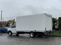 A 2024 Ford E-450 cube truck with a white cargo box parked on a wet surface