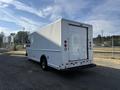 A white 2012 Ford Econoline cargo van with a boxy shape and rear loading door positioned at an angle
