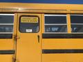 A yellow 2006 Thomas Saf-T-Liner HDX school bus with a sign reading Emergency Door Porte de Secours on the door