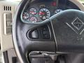 Close-up of the steering wheel and dashboard controls of a 2011 International WorkStar showing cruise throttle buttons and various gauges