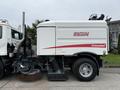 A 2009 UD Trucks UD 3300 street sweeper with a large round broom on the front and a vacuum intake on the side is parked with branding visible on the body