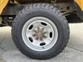 Close-up of a large all-terrain tire mounted on a silver wheel showcasing the rugged tread pattern and multiple lug nuts
