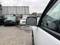 A 2011 Chevrolet Colorado is parked with its side mirror visible, showing a rainy day and blurred vehicles in the background