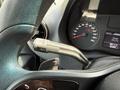 A close-up view of the steering wheel and gear lever of a 2023 Mercedes-Benz Sprinter showing dashboard indicators and controls