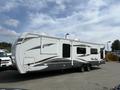 A 2013 Outdoor Wind River travel trailer featuring a sleek design with white and gray accents and dual axles