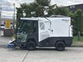 A 2019 Madvac LS175 urban cleaning unit with a front-mounted broom, designed for street cleaning and waste collection, featuring a compact design and large wheels