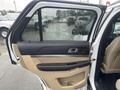 A 2016 Ford Explorer with an open front door showcasing the interior door panel and controls