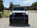 A 2021 Jeep Wrangler in white with black accents is parked with its front view clearly visible showcasing its iconic grille and rugged design