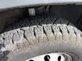 Close-up of a rugged tire with deep treads mounted on a 2017 RAM Promaster showcasing wear and dirt on the surface