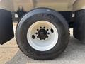 Close-up of a Dunlop tire mounted on a white rim belonging to a 2010 Freightliner M2 106 vehicle