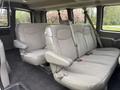 A 2004 Chevrolet Express interior with two rows of grey upholstered seating featuring seatbelts and a spacious design