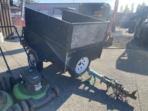 A trailer with a wooden bed and white wheels is positioned next to three Honda Lawnboy mowers and two Stihl line trimmers