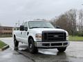 A white 2008 Ford F-250 Super Duty pickup truck parked with a black grill and large headlights facing the viewer
