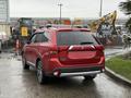 A red 2016 Mitsubishi Outlander parked with a blank license plate visible and a roof rack attached