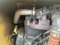 Close-up of the engine compartment of a 2010 Vermeer Corporation BC1000XL with visible mechanical components and a large exhaust pipe