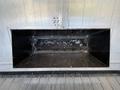 A metallic opening in a Freightliner M2 106 truck bed with a dark interior, showing signs of dirt and debris inside