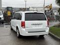 A white 2017 Dodge Grand Caravan parked with its rear visible showing its distinctive tail lights and emblem