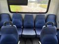 A row of five blue upholstered seats with black seat belts in a vehicle interior