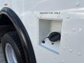 A close-up of the fuel filler neck of a white 2012 Ford Econoline with a black cap labeled unleaded fuel only