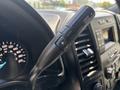 Close-up of the gear shift lever on the steering column of a 2019 Ford F-150 featuring buttons for drive mode adjustment and gear selection