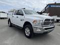 A white 2015 RAM 2500 pickup truck with chrome accents and a truck bed cover is parked with its front angled towards the viewer