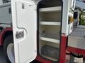 A white storage compartment with shelves is open on a 2012 International 7300 Workstar truck revealing empty space inside