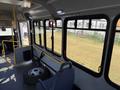 Interior view of a 2017 Chevrolet Express showing seating area and large windows with an empty space for passengers with a tire on the floor