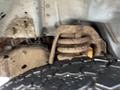 A close-up view of the suspension system of a 2006 Ford Econoline featuring rusted coil springs and part of a tire visible in the foreground