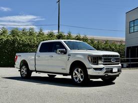 A 2023 Ford F-150 pickup truck in white with chrome accents parked with its driver's side facing the viewer and the front slightly angled toward the left