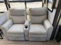 A light-colored leather reclining sofa with two seats and built-in armrests each featuring a cup holder