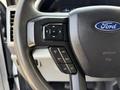 Close-up of the steering wheel of a 2020 Ford F-350 SD featuring buttons for cruise control and a Ford emblem on the center hub