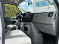 Interior view of a 2018 Ford Econoline showcasing the driver's seat dashboard and center console with gray fabric upholstery and controls visible