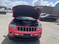 A red 2015 Jeep Grand Cherokee with the hood open showcasing the engine compartment