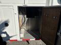 A partially open door reveals the interior storage compartment of a 2006 Freightliner M2 106 with visible metal wiring and a clean floor surface