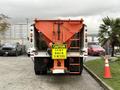 A 2012 International 7400 truck with a large orange snowplow attachment at the front displaying a caution sign that reads stay back 15 meters