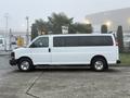 A white 2016 GMC Savana van with side windows and a light mounted on the roof, parked on a gray surface