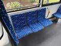 Three blue patterned seats inside a 2018 Grande West Vicinity bus with a brown textured surface and a metal handrail nearby
