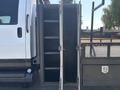 A 2005 GMC C7500 Topkick with an open storage compartment on the side featuring multiple shelves for organizing equipment or tools