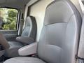 Interior view of a 2008 Ford Econoline showing two light gray upholstered front seats with armrests and a steering wheel in the foreground