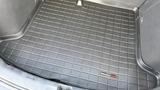 A black rubber cargo mat with a textured grid pattern designed for a 2019 Nissan Kicks